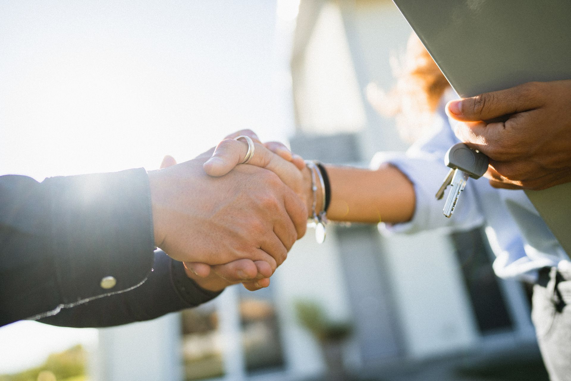 A man and a woman are shaking hands in front of a house.