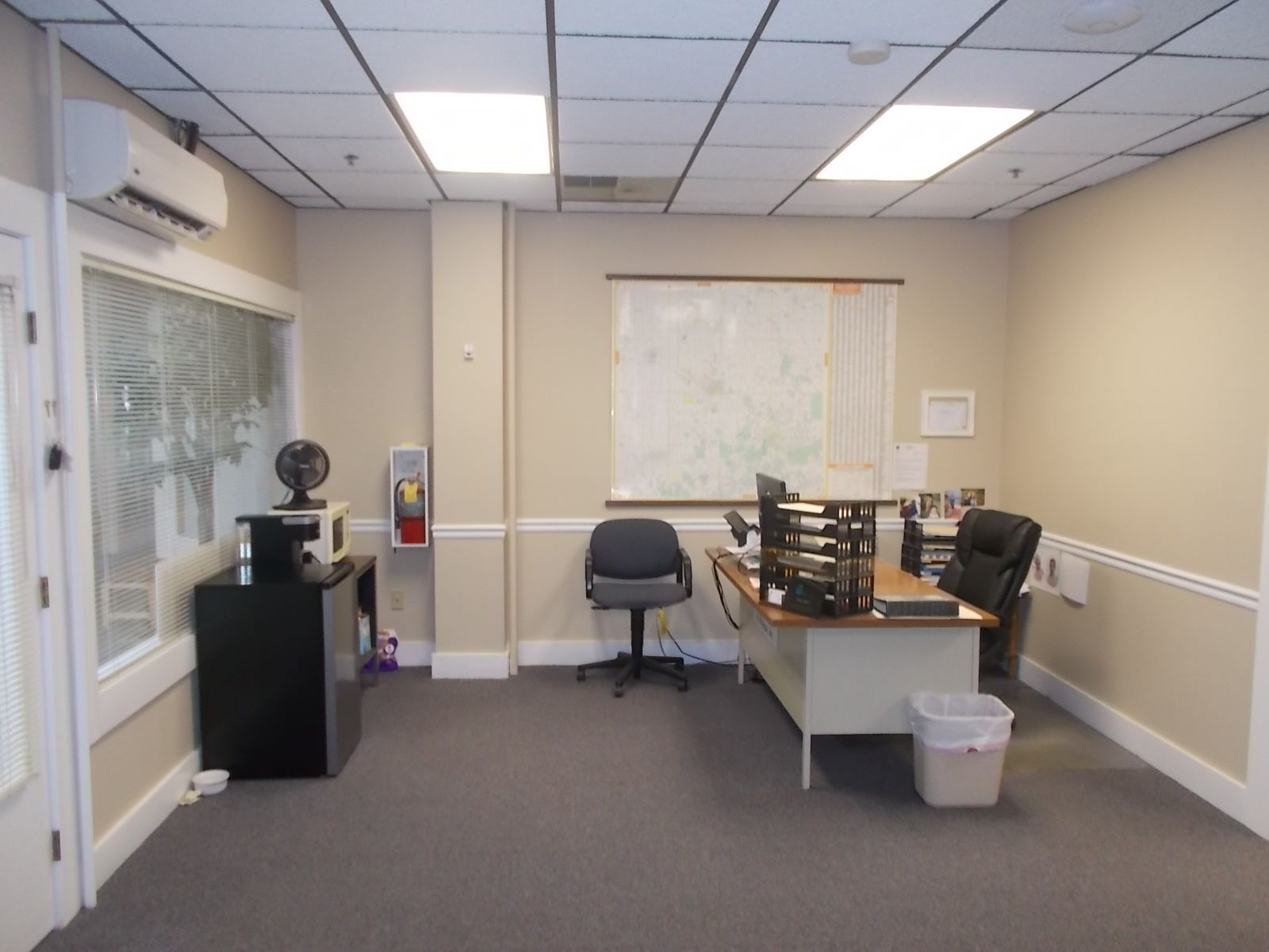 An office with a desk and chairs and a fan