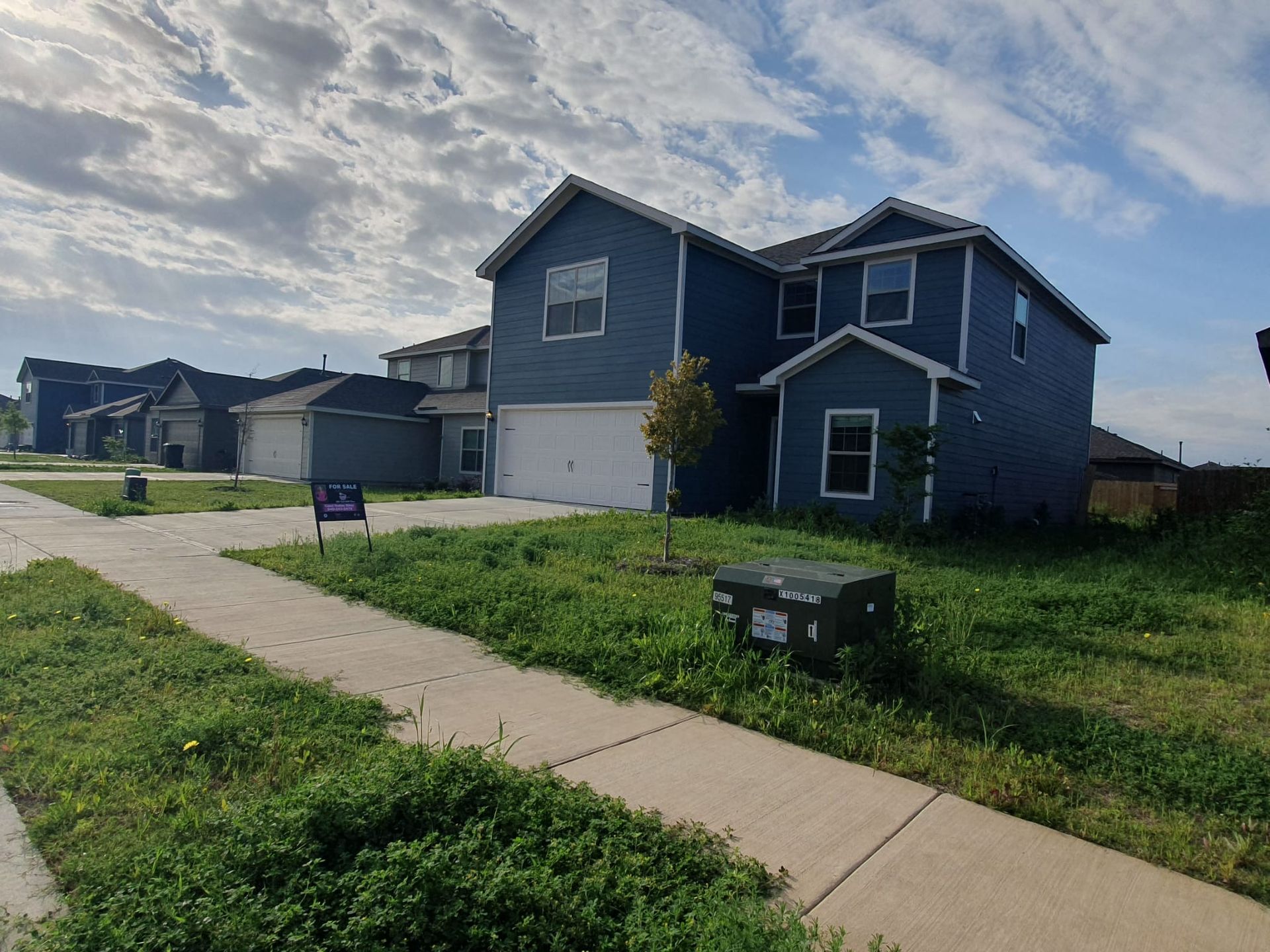 A blue house with a for sale sign in front of it