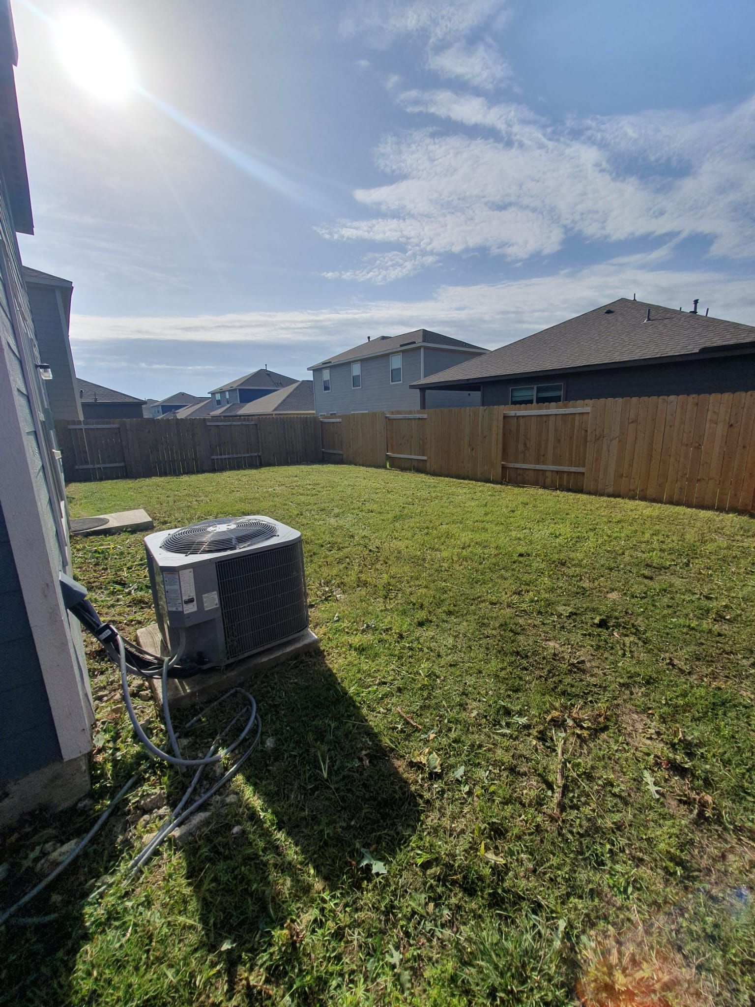 A backyard with a fence and a heater in the grass.