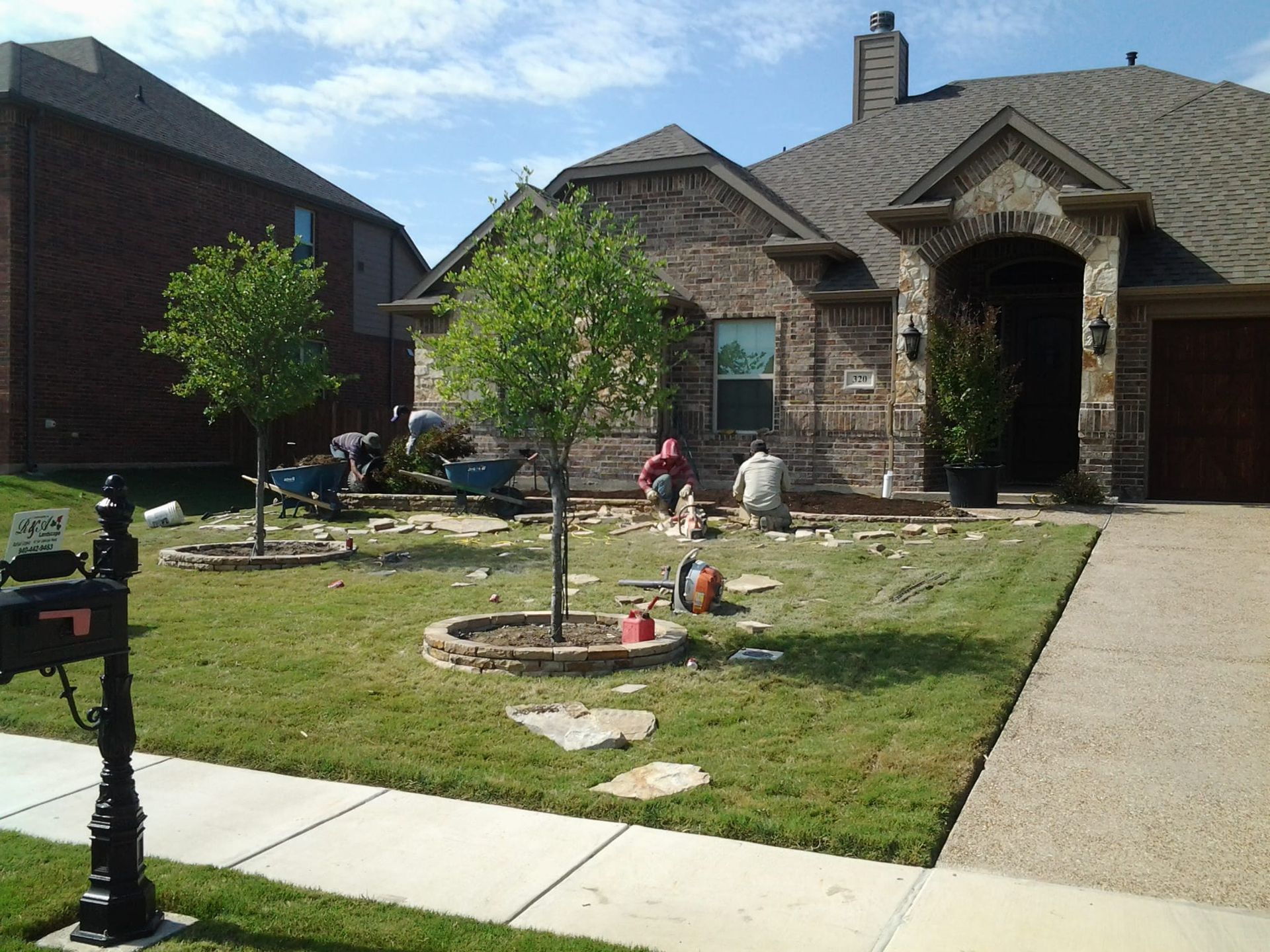 A mailbox in front of a brick house with the letter t on it