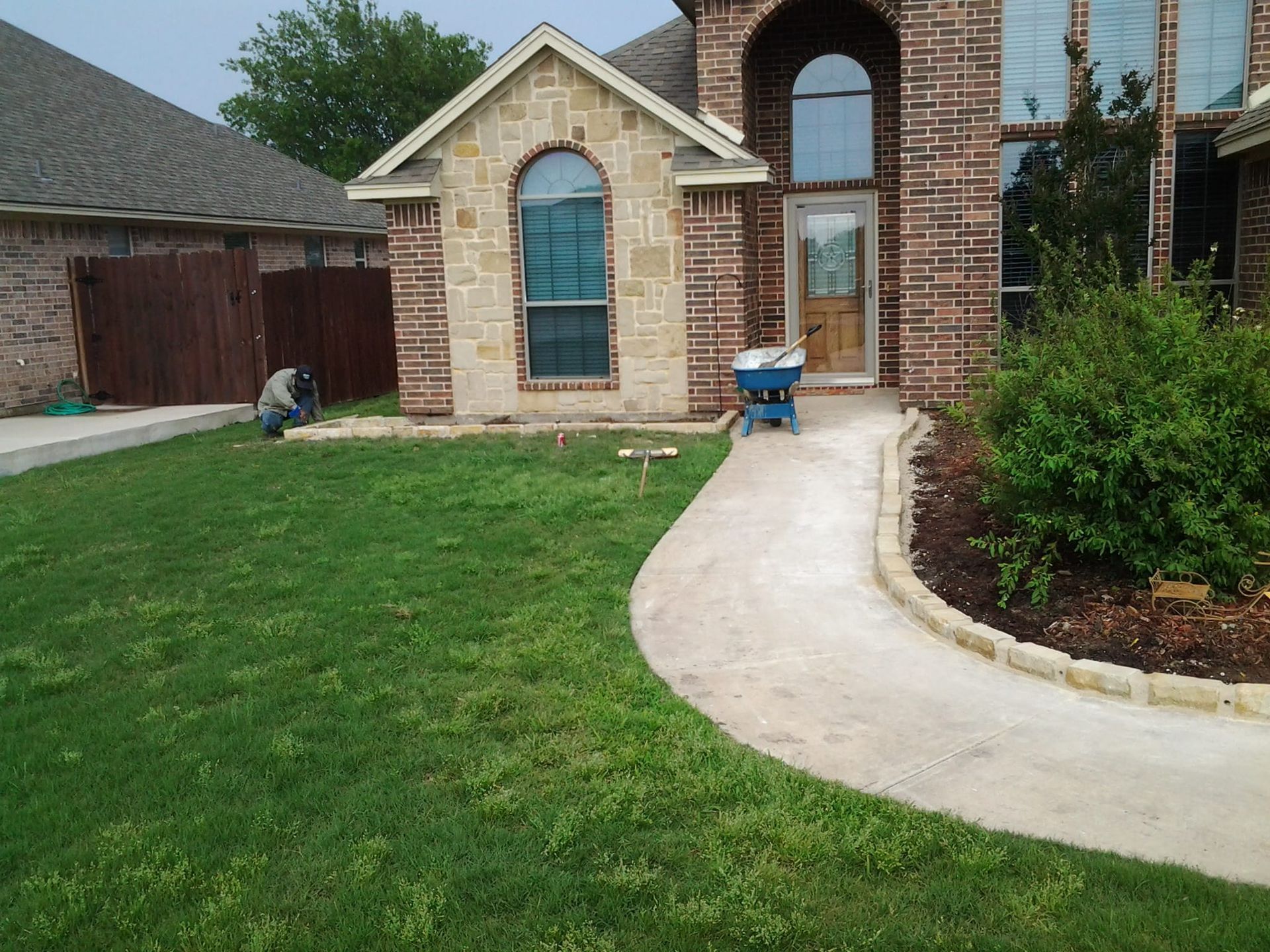 A brick house with a blue wheelbarrow in front of it