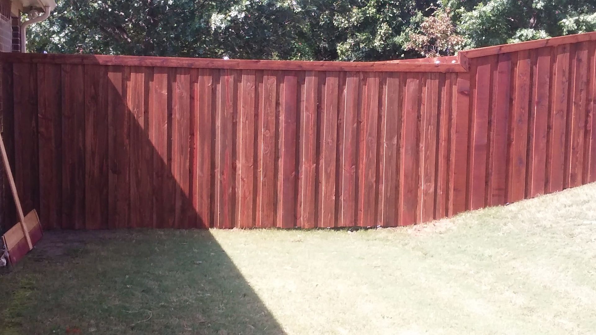 A red wooden fence is sitting on top of a lush green lawn.