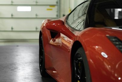 A red sports car is parked in front of a garage door