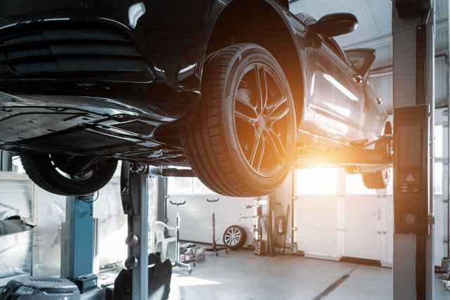 A car is sitting on a lift in a garage.