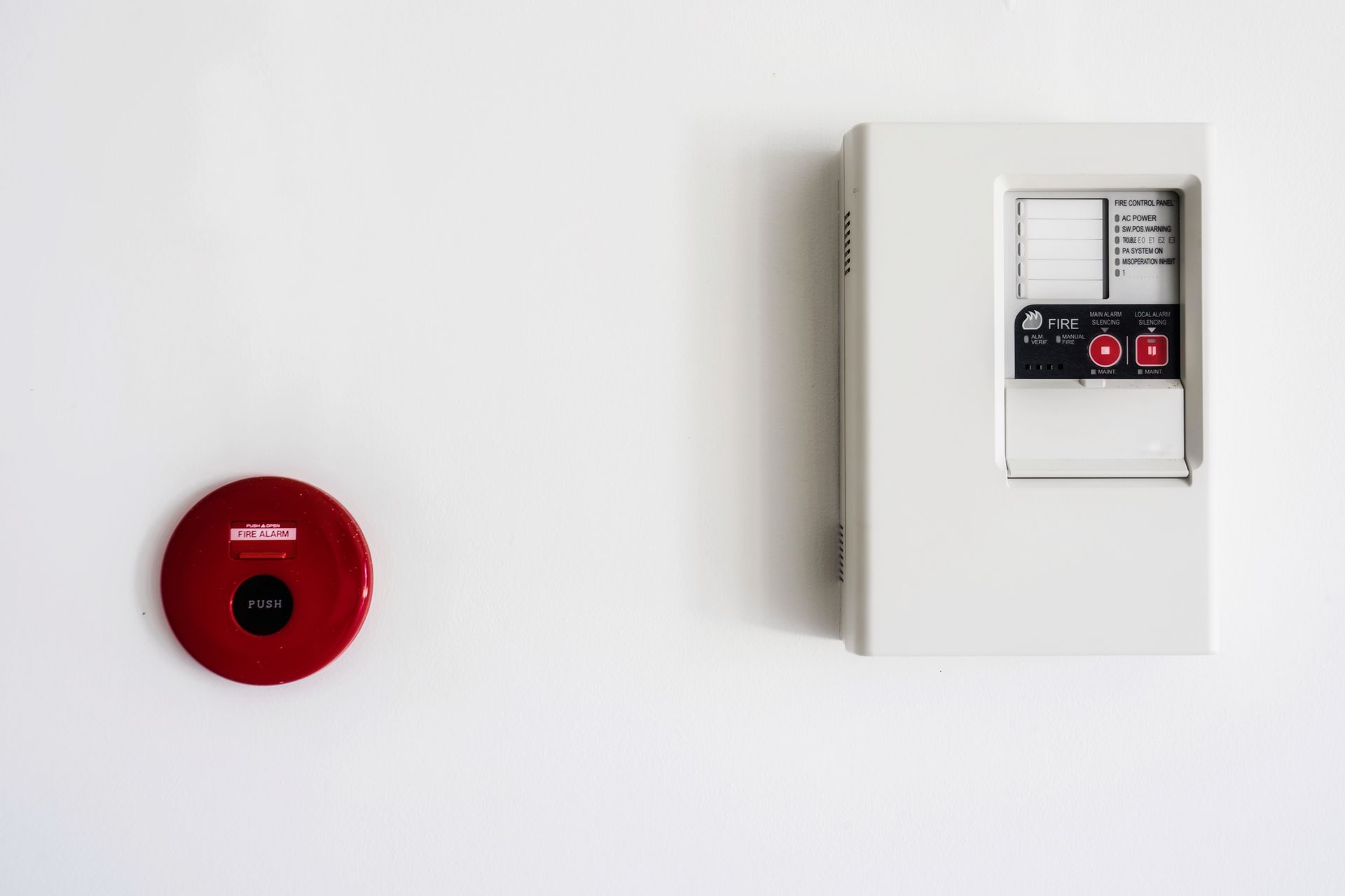 A red fire alarm and a white fire alarm on a white wall.
