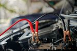 A close up of a car battery being charged with jumper cables.
