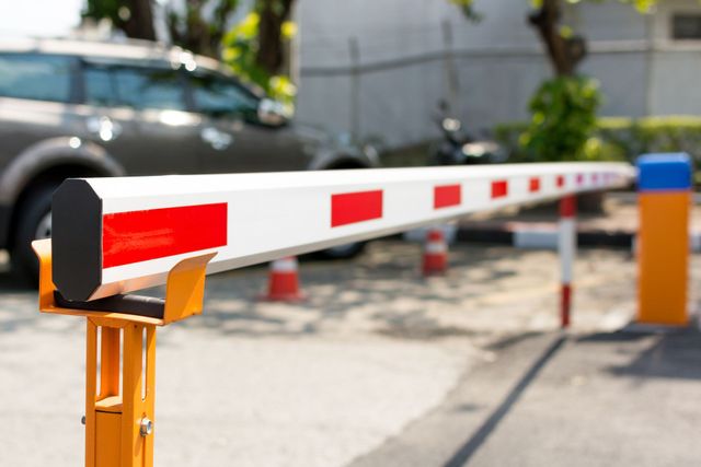 A car is parked behind a barrier in a parking lot.