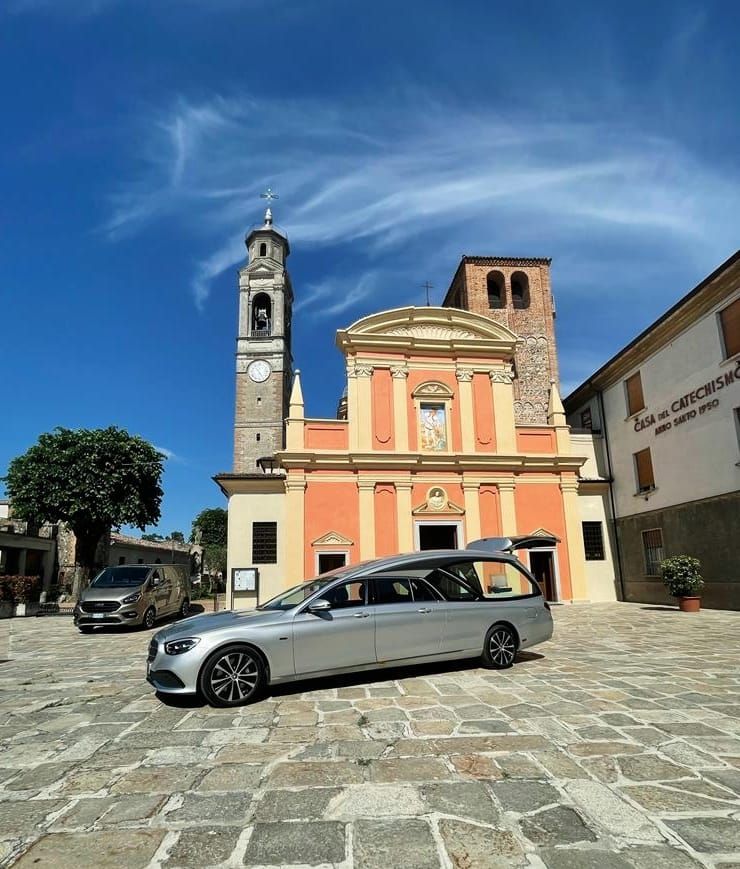 Una bara di legno con composizione floreale in un carro funebre.