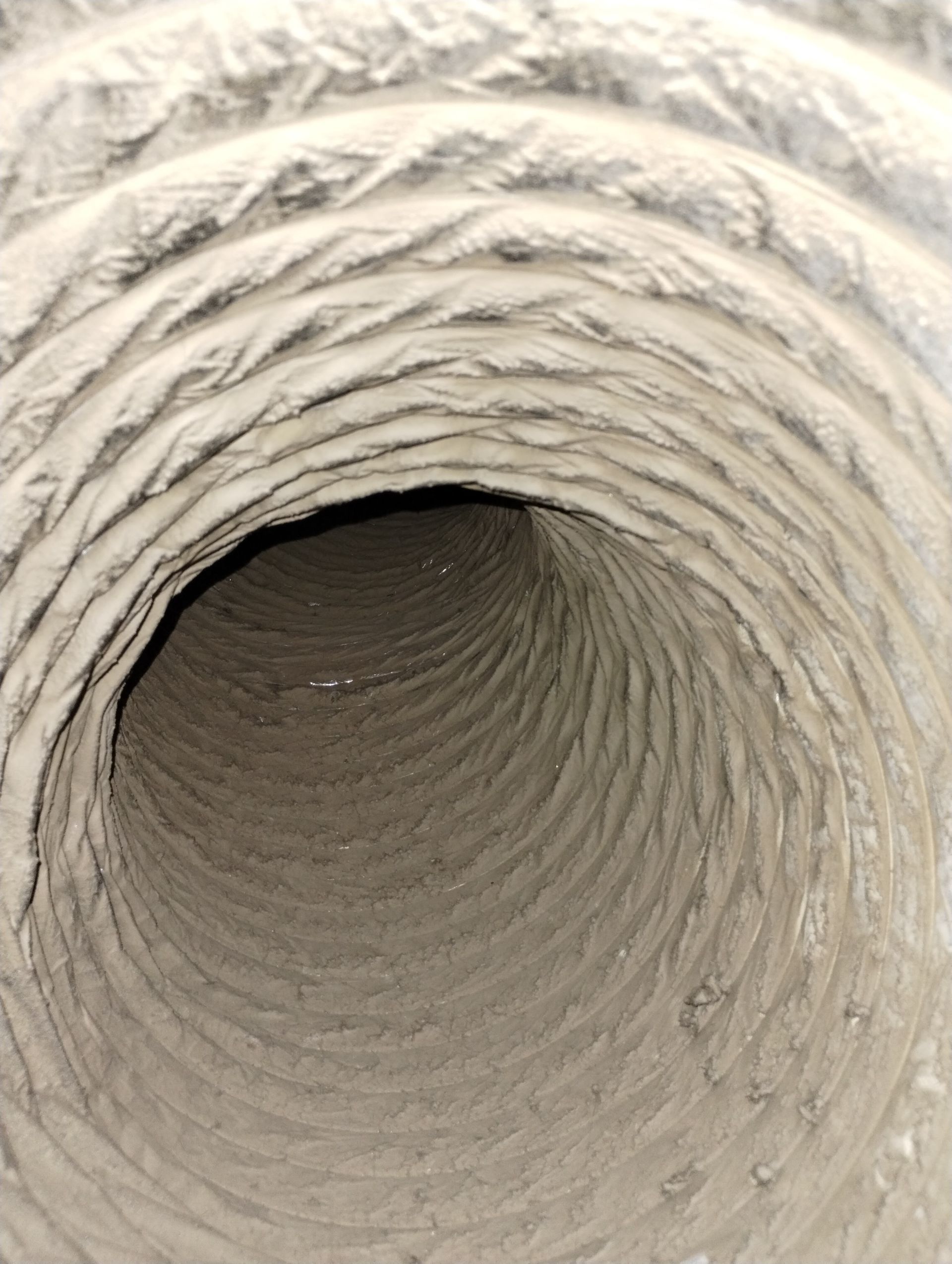 A close up of a dirty air duct with a hole in the middle