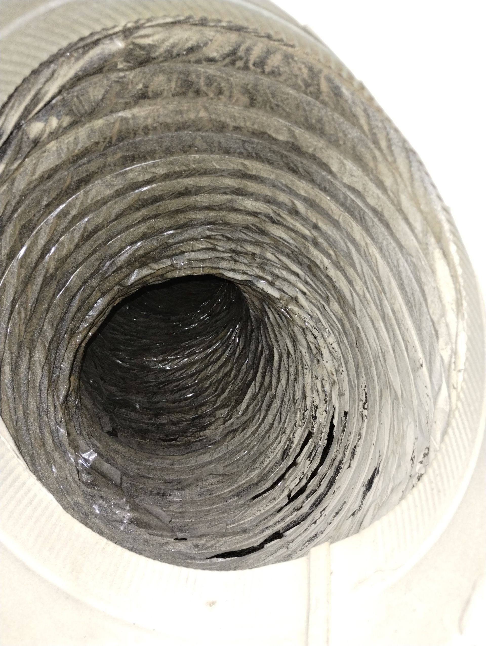 A close up of a dirty air duct on a white background