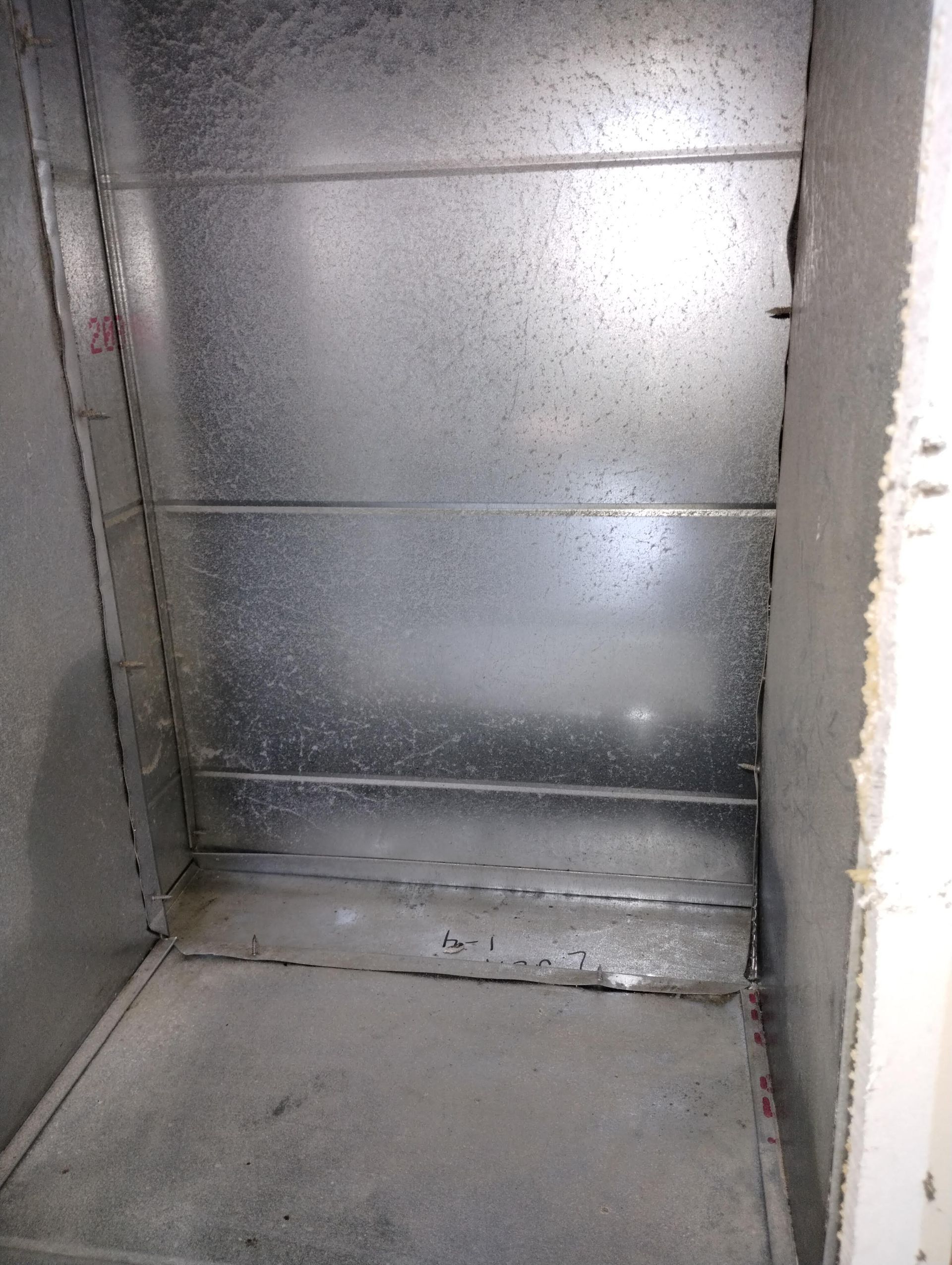 The inside of a metal cabinet with a concrete floor