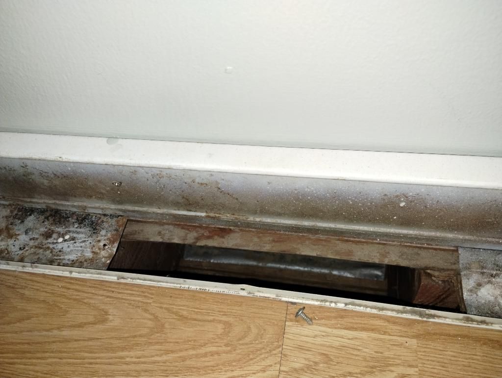 A close up of a hole in a wall next to a wooden floor