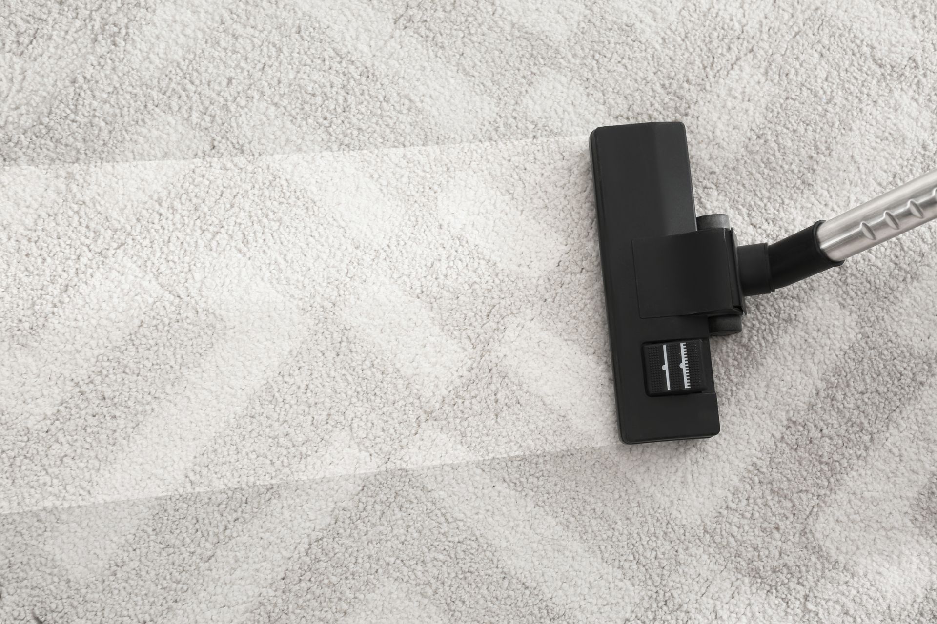 A vacuum cleaner is cleaning a white carpet.