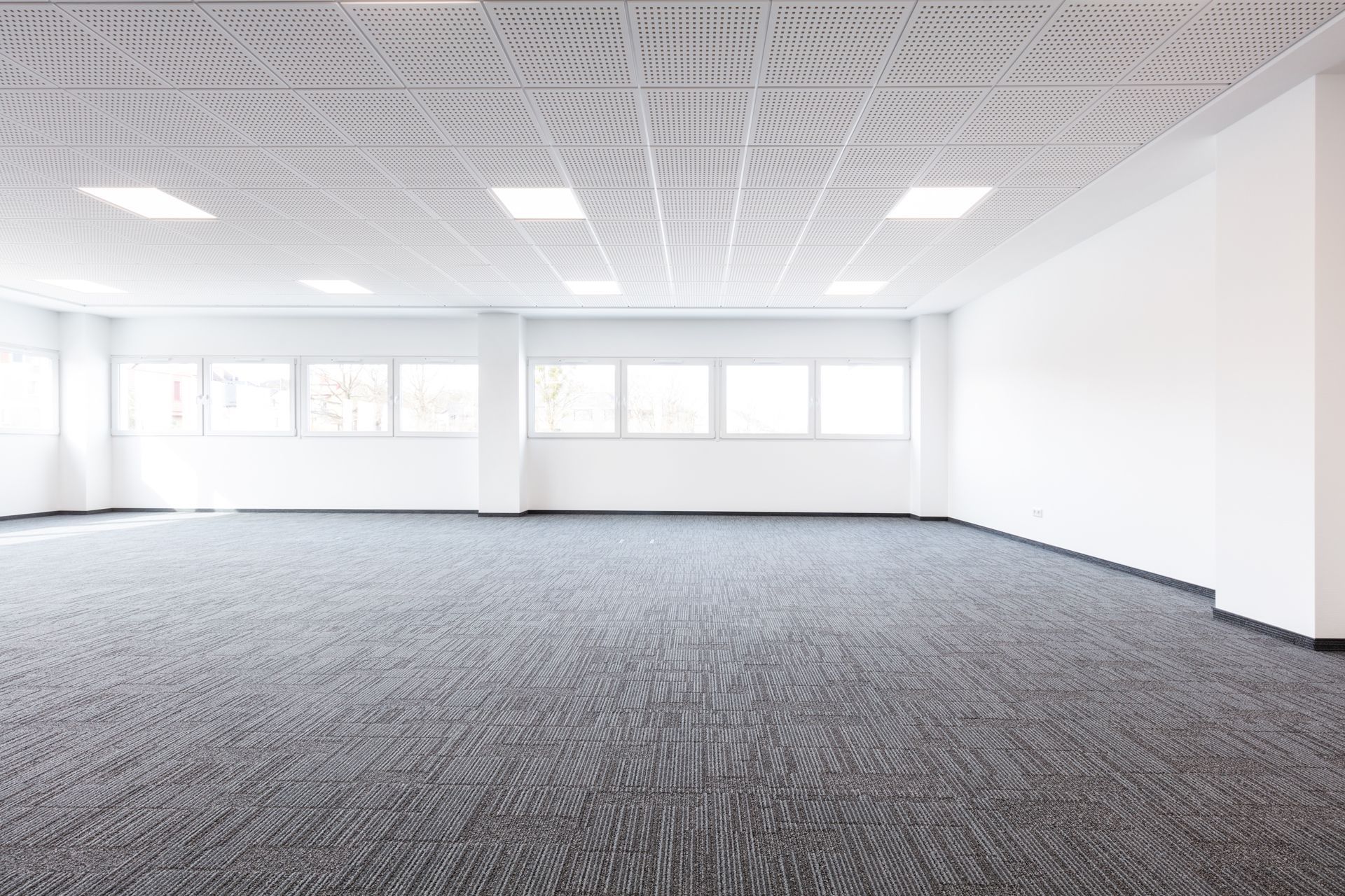 An empty office with a carpeted floor and white walls