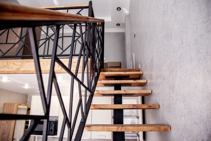 Indoor stairs with wooden treads and metal railings.
