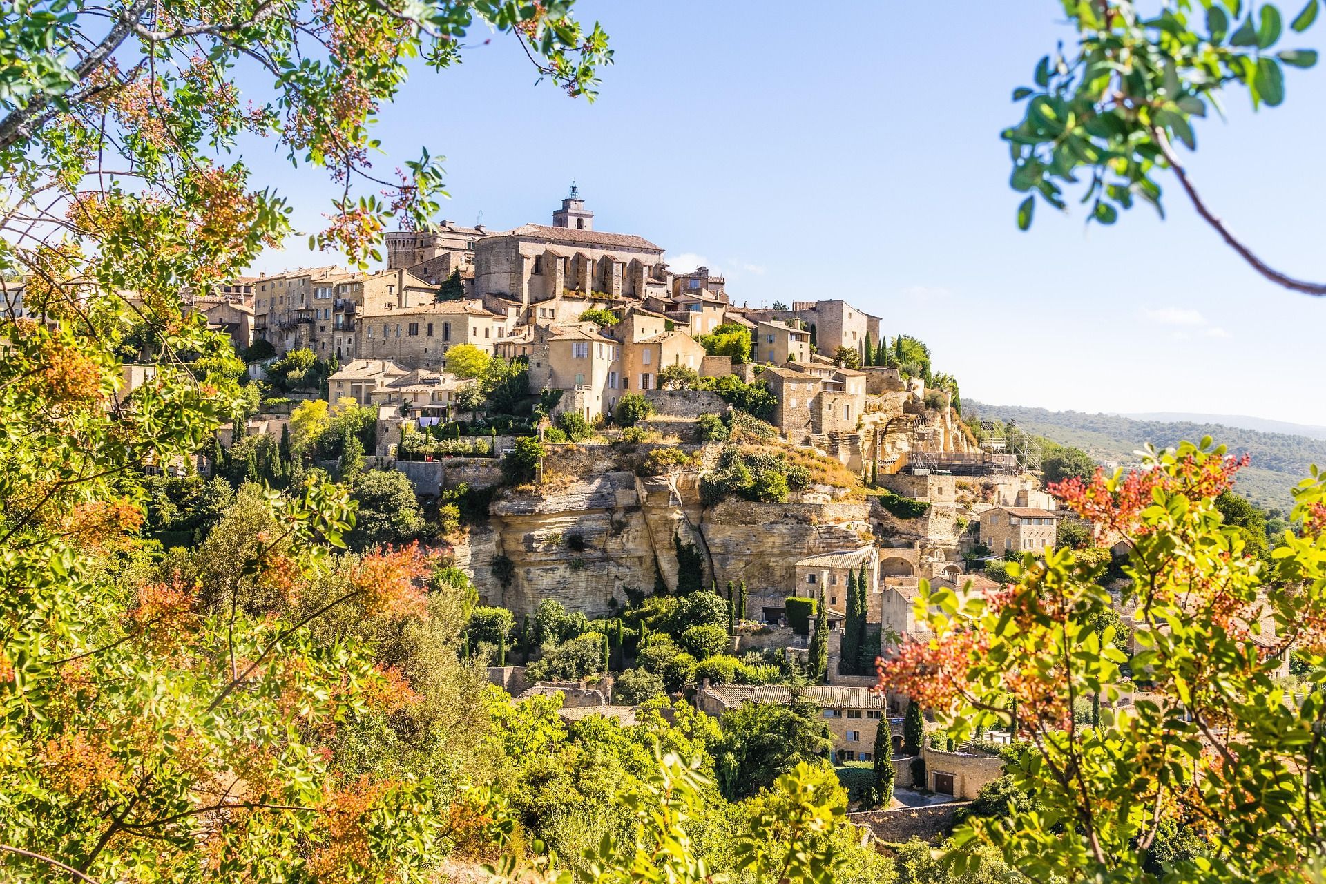A Fountain, CO village with historic buildings built into a rocky hillside under a bright blue sky.