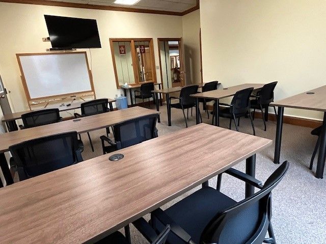 A classroom with tables and chairs and a whiteboard.