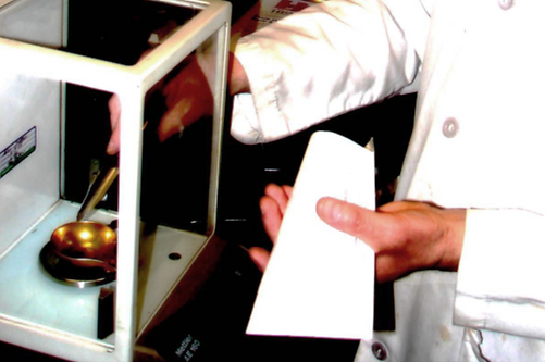 A person in a lab coat is holding a piece of paper