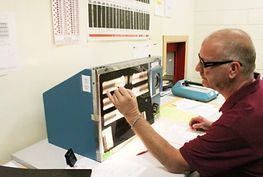 A man is sitting at a desk working on a machine.