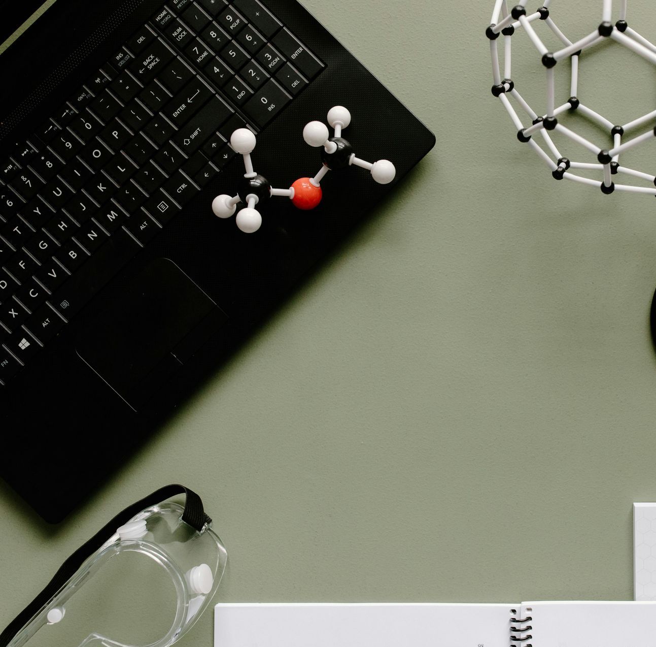 A laptop with a model of a molecule on the keyboard