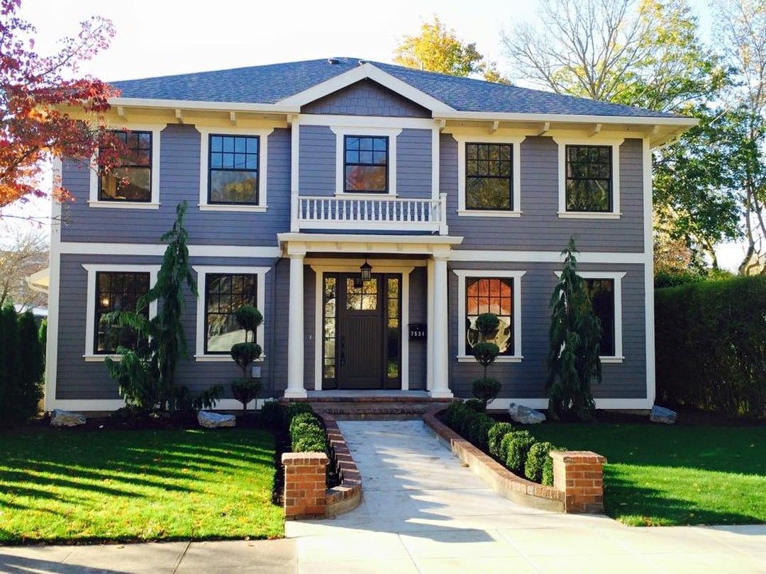 Two-story blue house with white trim, a brick walkway, and green lawn.