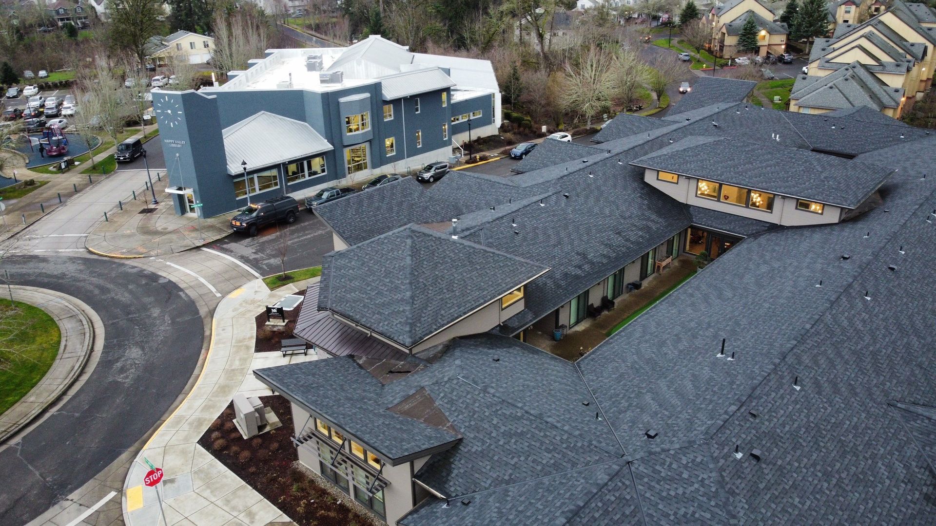 Aerial view of buildings with dark grey roofs, landscaping, and a circular drive.