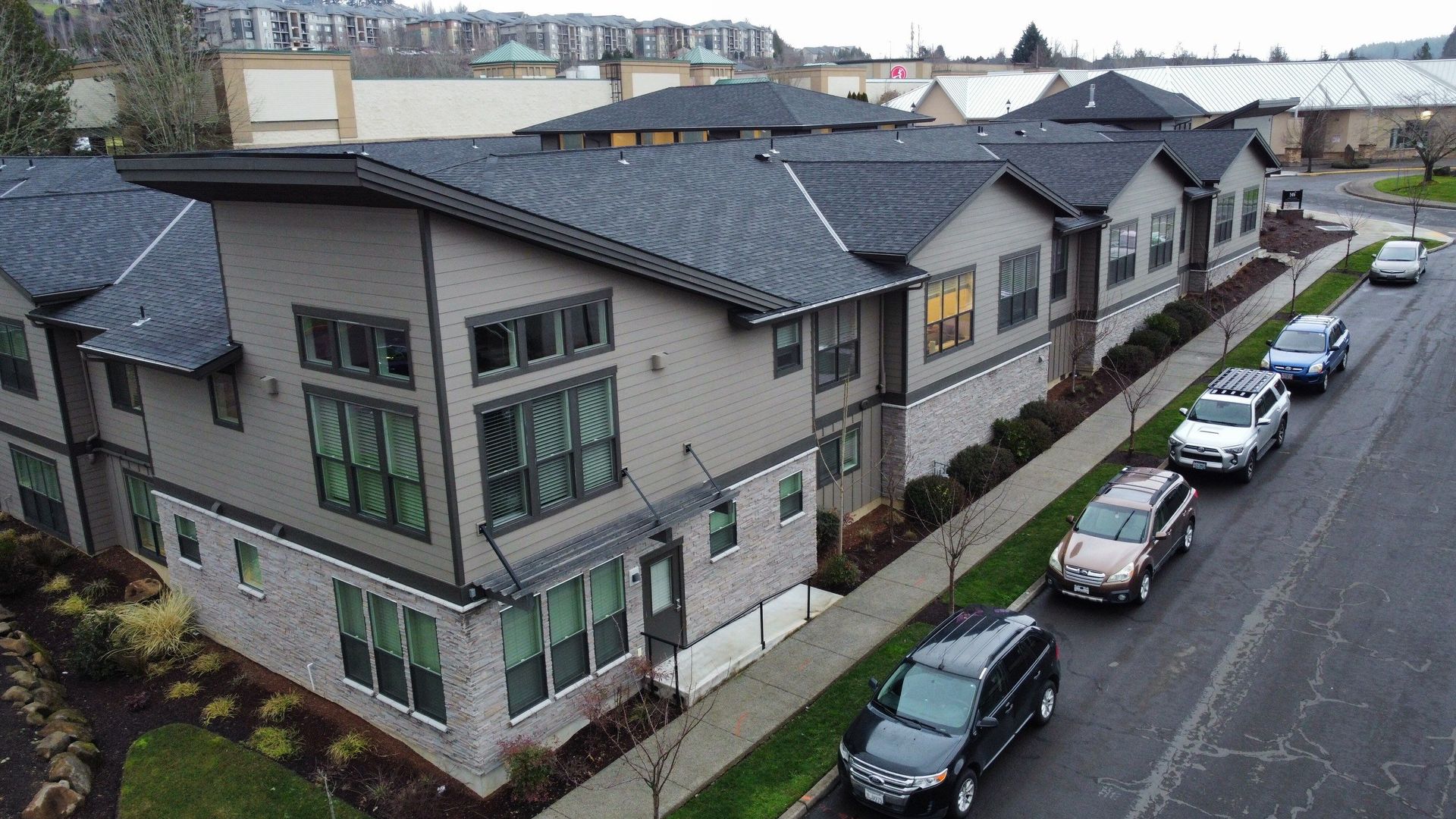 Modern gray and beige townhomes with cars parked on the street.
