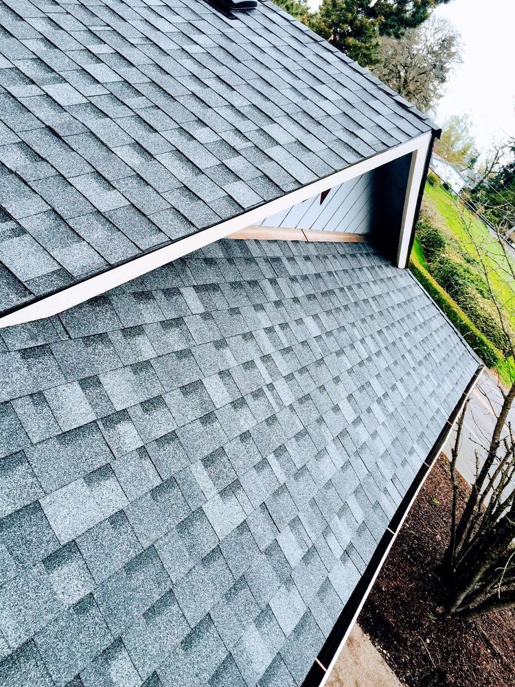 Gray shingle roof on a house, seen from above with a lush green lawn on the right.