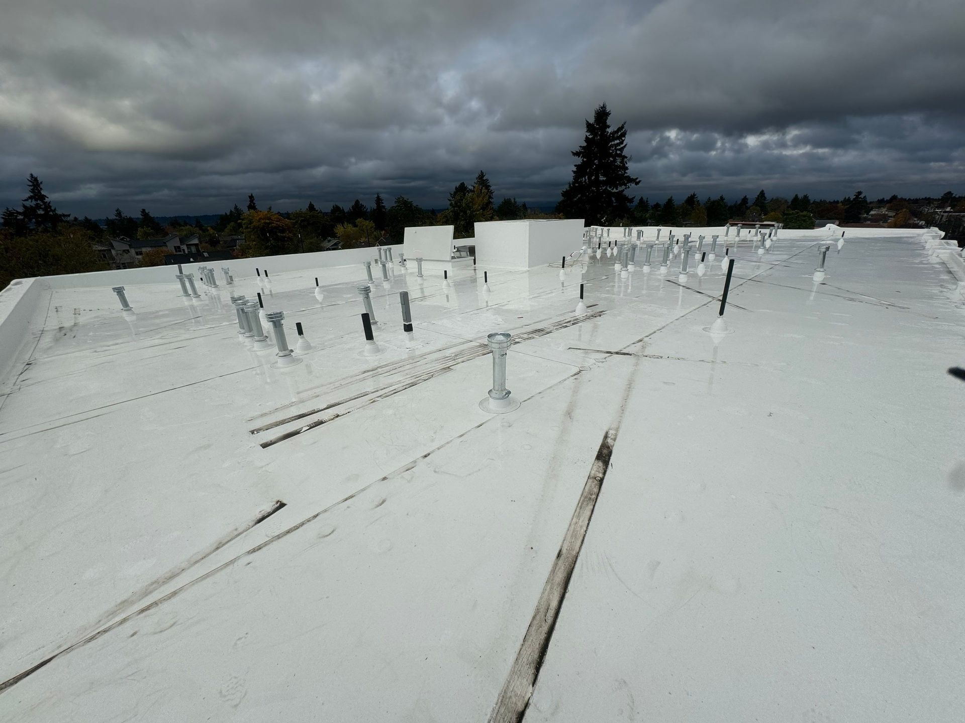 White flat roof with various vents and a cloudy sky in the background.
