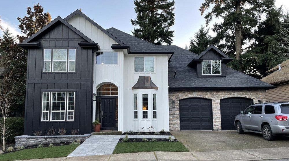 Two-story house with black and white exterior, brick accents, and a SUV parked in front.