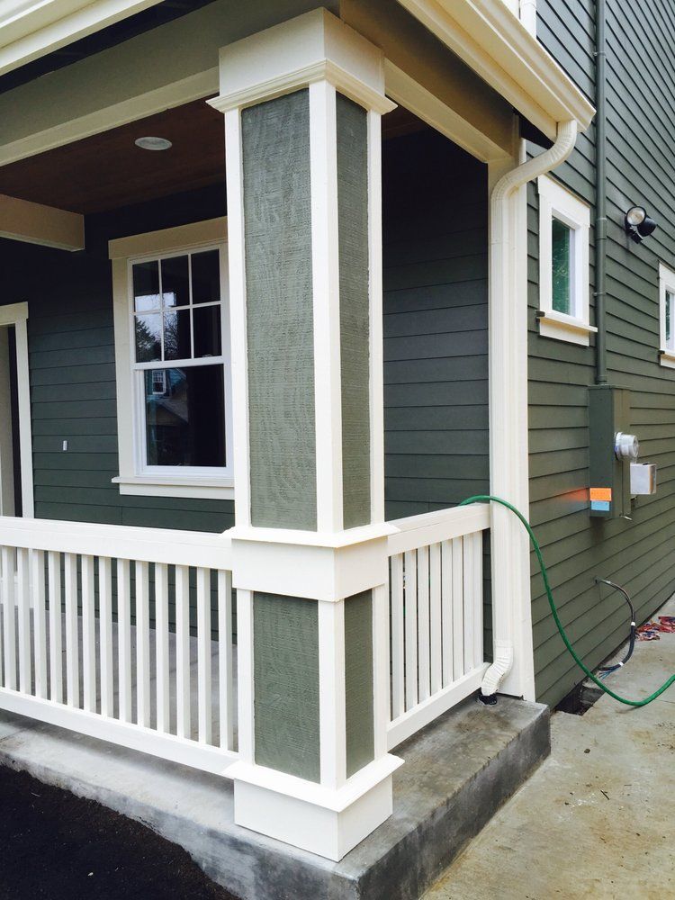Green house exterior with white trim. Porch with white railing and pillar.