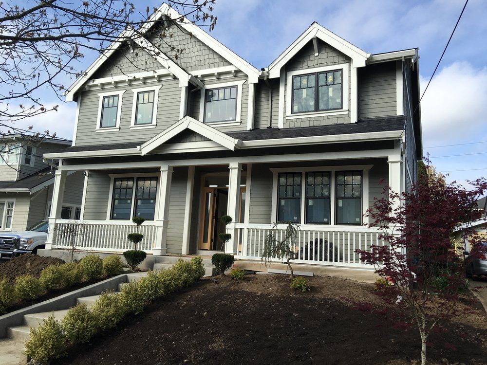 Two-story gray house with white trim, porch, and steps leading up to the entrance.