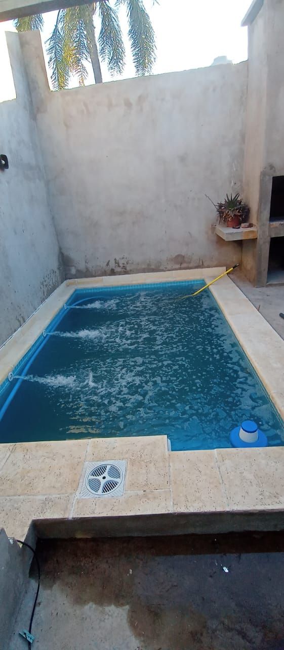 Pequeña piscina rectangular al aire libre. Agua azul claro. Paredes y suelo de hormigón.