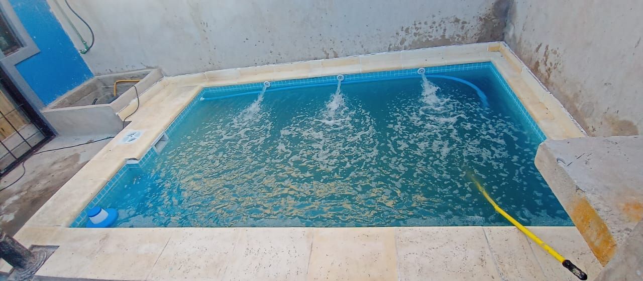 Una pequeña piscina rectangular con agua burbujeante en un entorno rodeado de cemento.