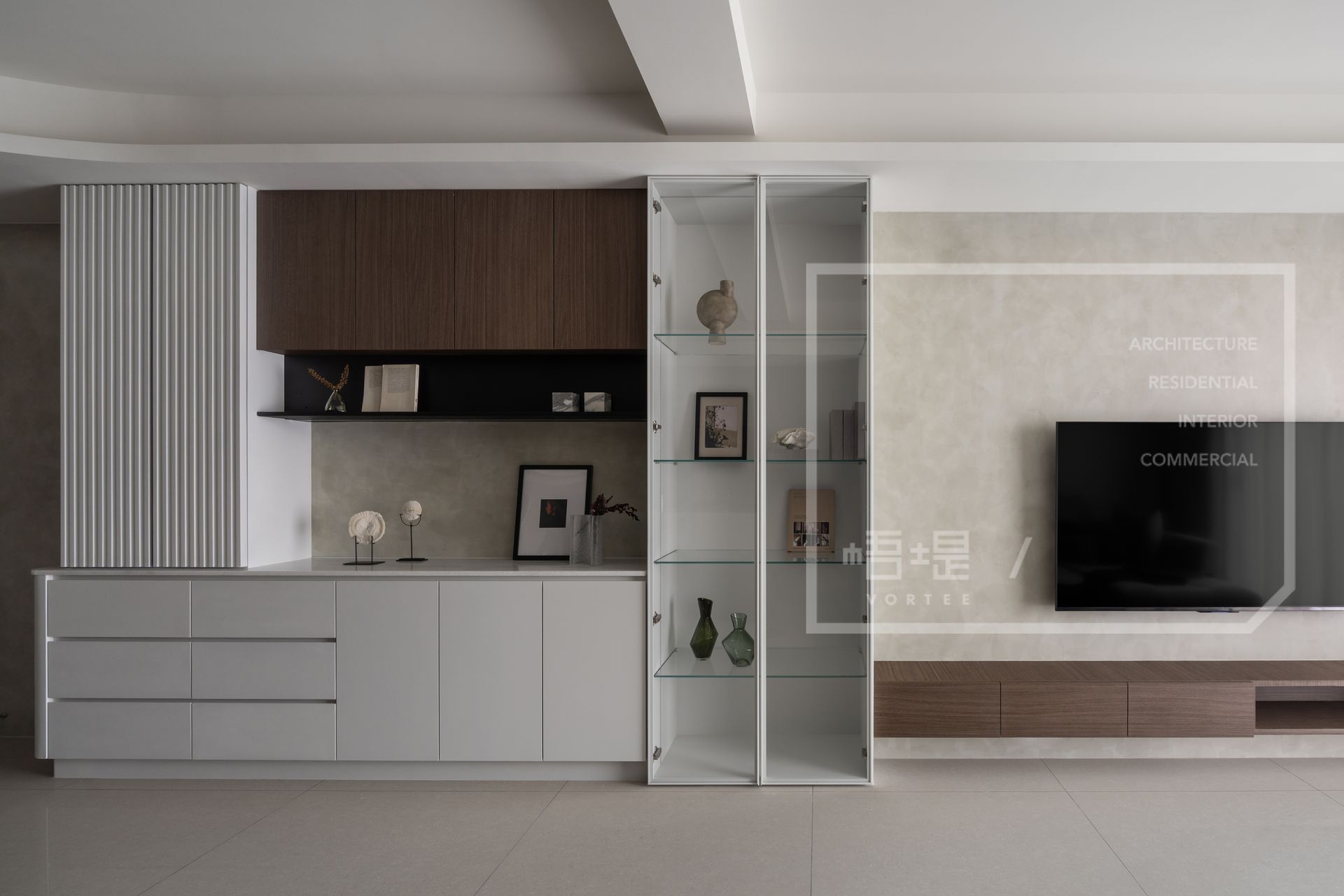 台南梧堤空間設計示範客廳電視牆的櫃體設計關鍵：採用不落地懸浮式白色底櫃減輕量體，並巧妙搭配溫潤木紋開放層架與具備穿透感的玻璃展示櫃，在滿足海量居家收納需求的同時，更有效放大視覺坪數與整體空間感。