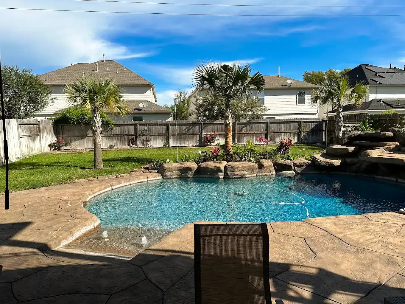There is a large swimming pool in the backyard of a house.