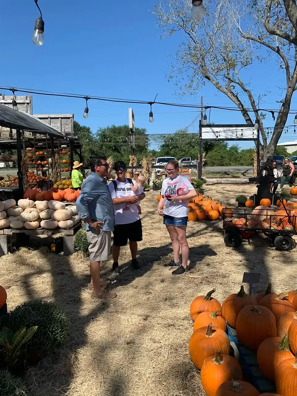 A group of people are standing in a pumpkin patch.