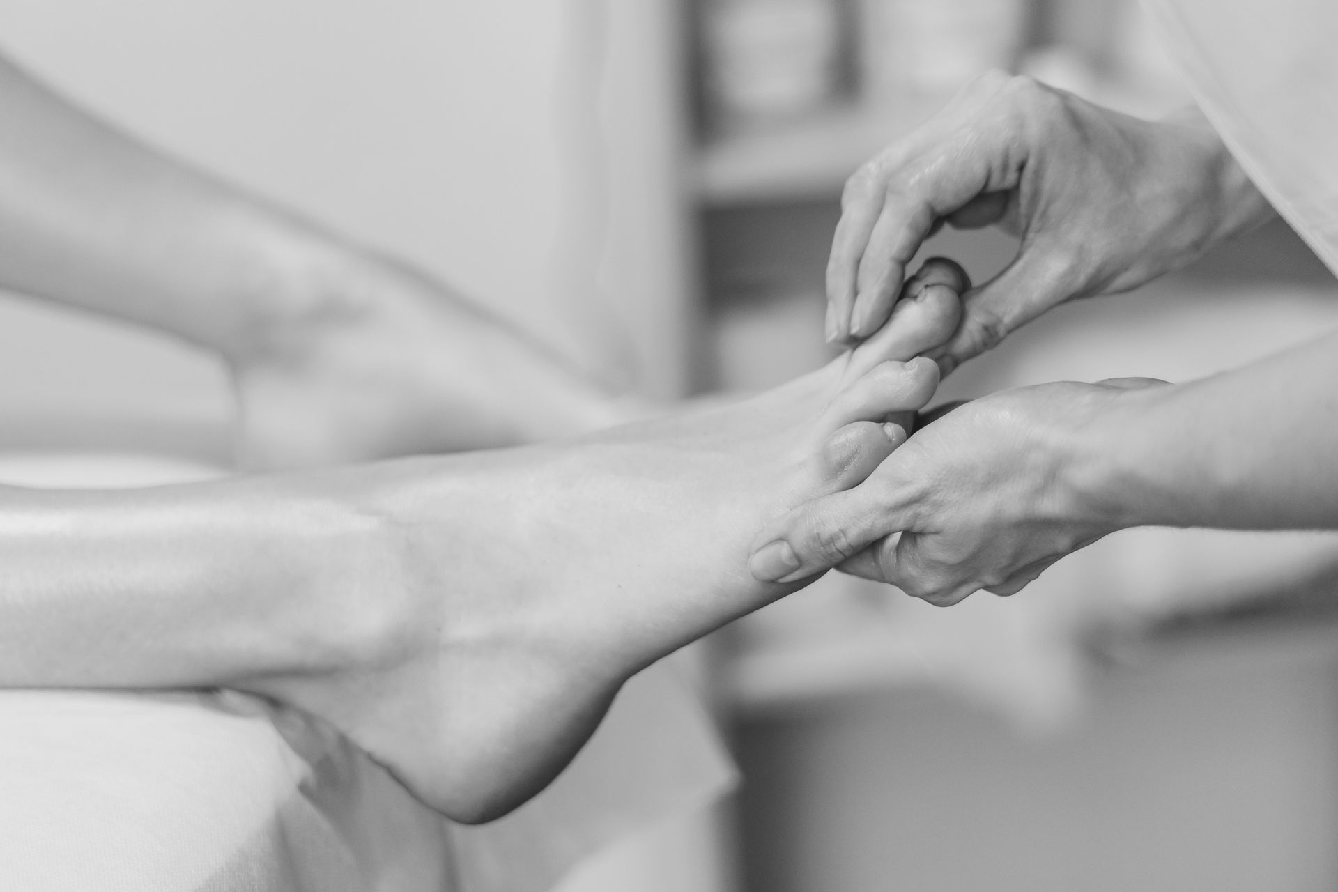 A healthcare professional smiling, treating a patient's leg on a massage table indoors.