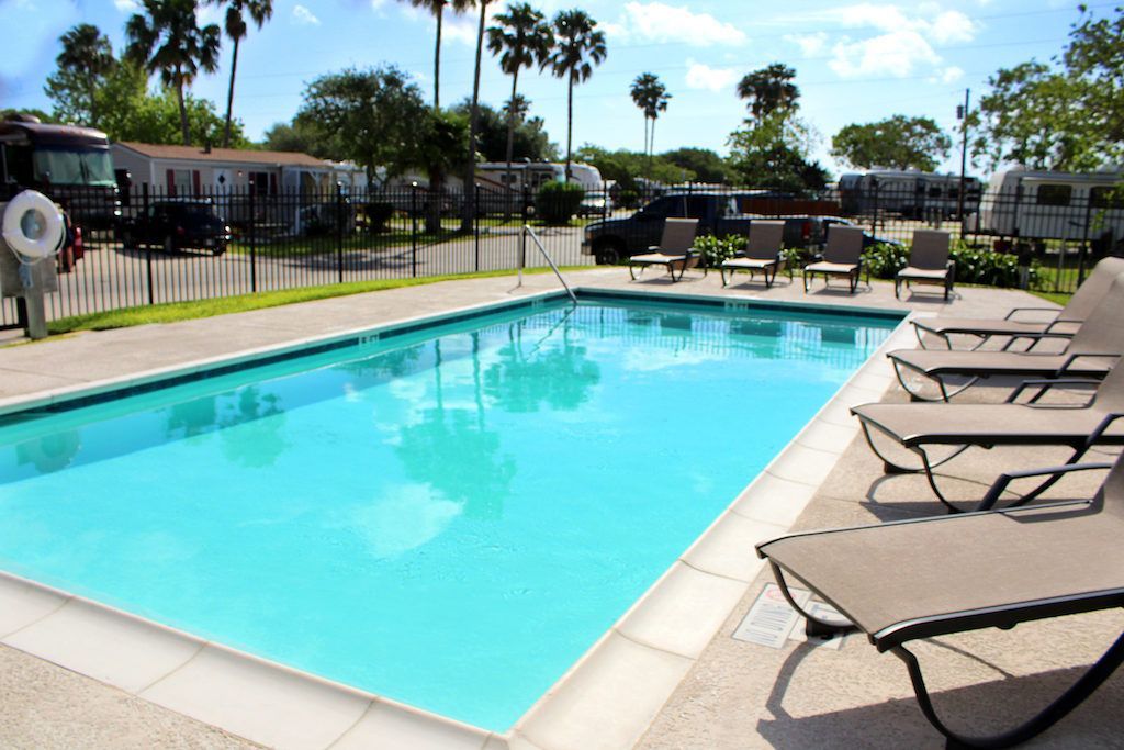 A large swimming pool surrounded by chairs and palm trees