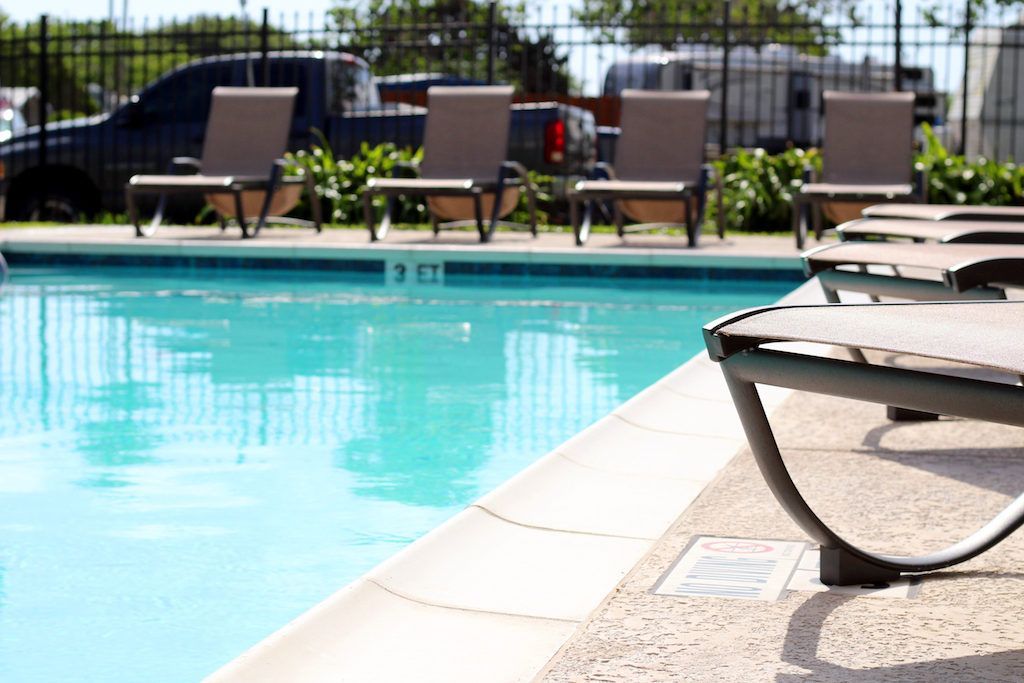 A swimming pool with chairs and a truck in the background