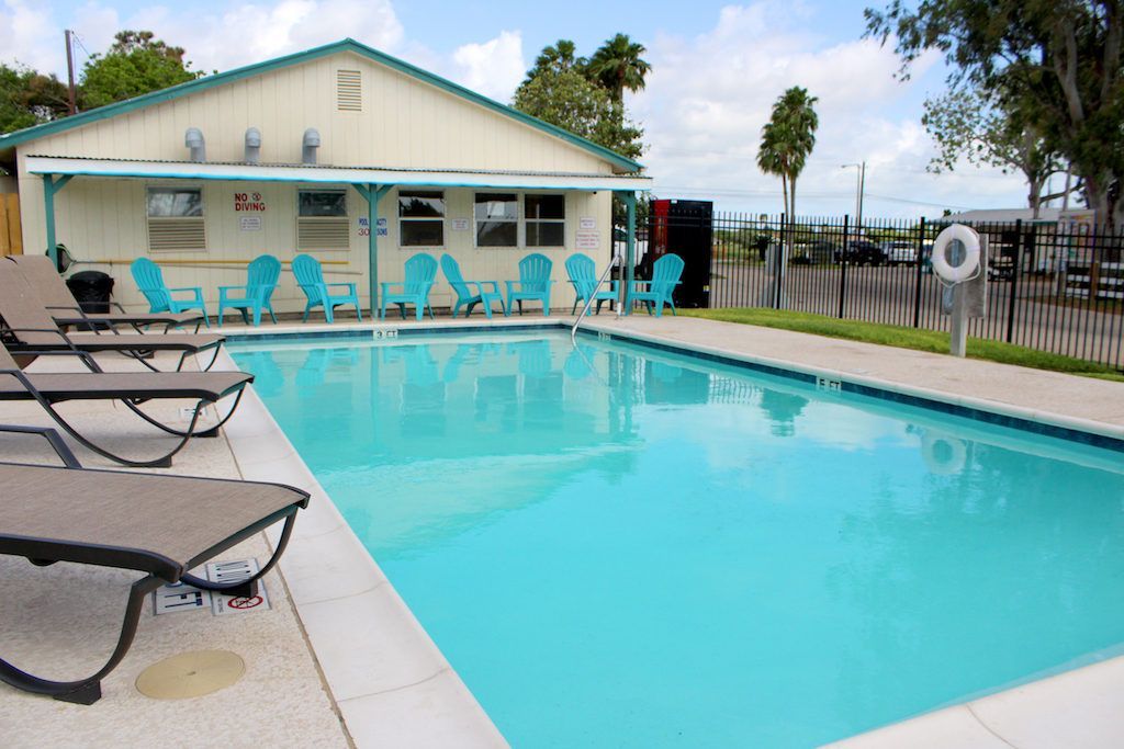 A large swimming pool surrounded by chairs and a building