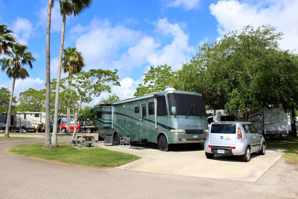 A rv parked in a lot with a car parked next to it.