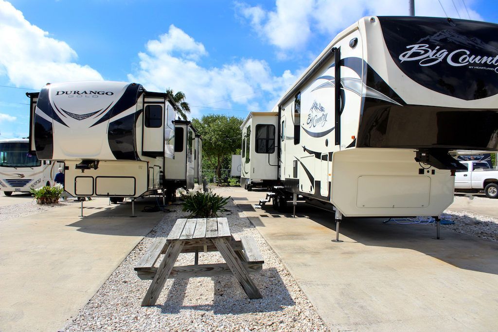 A row of rvs parked next to each other with a picnic table in the middle
