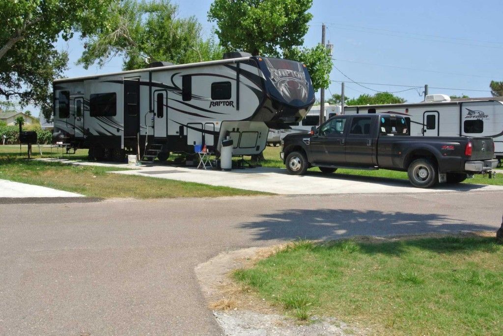 A truck is parked next to a rv in a park.