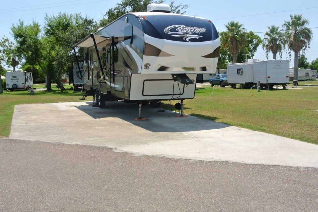 A camper is parked in a lot with trees in the background