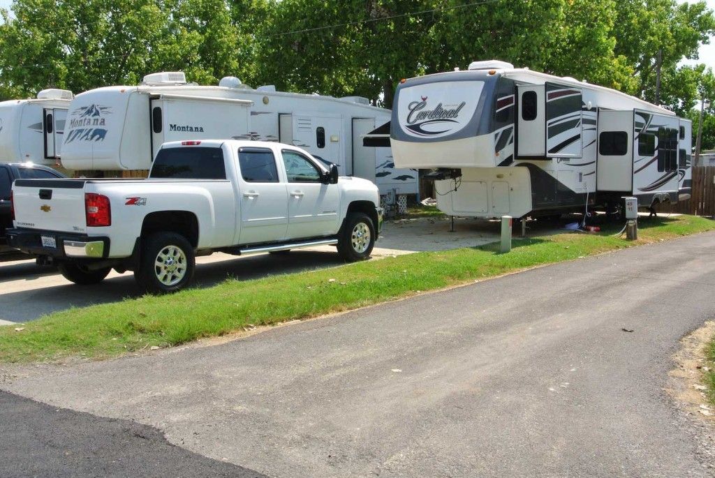 A white truck is parked next to a row of trailers
