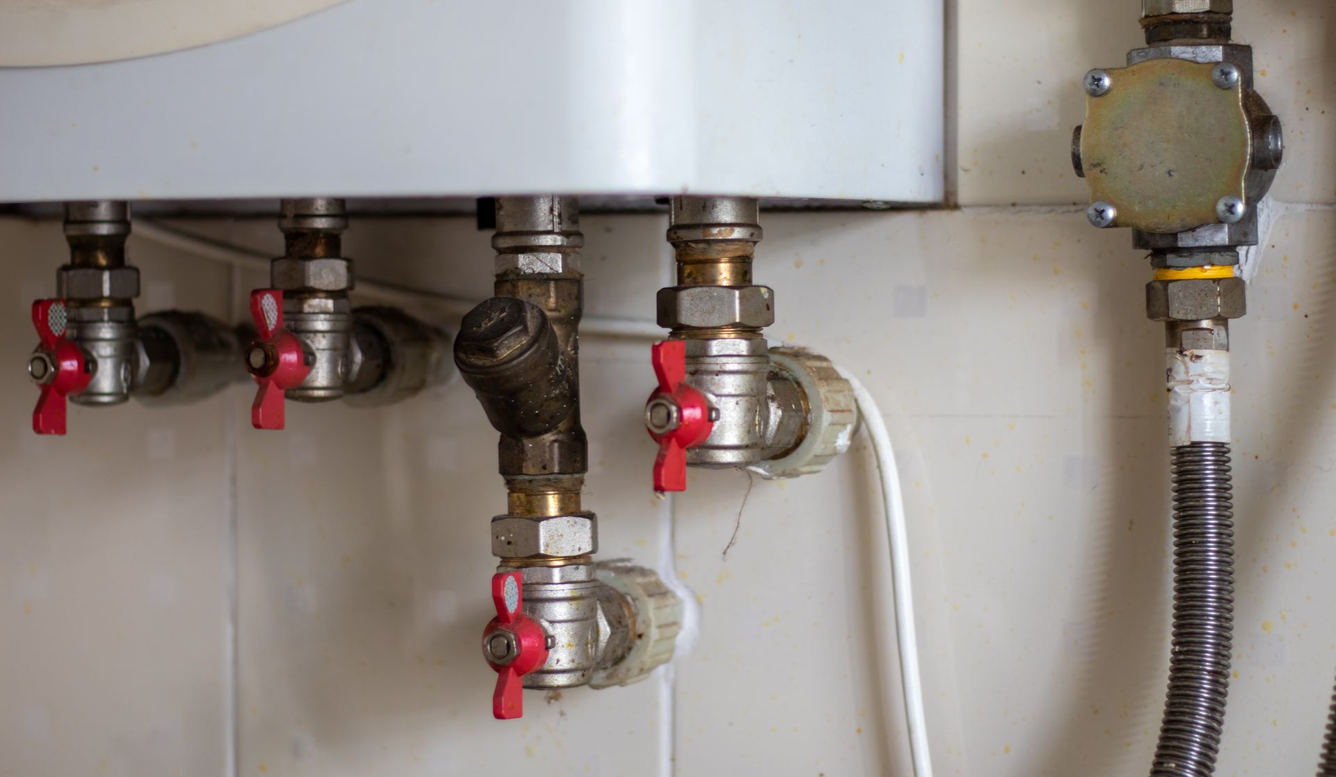 Close-Up of A Wall-Mounted Boiler with Several Red-Handled Valves and Metallic Pipes — Weav Plumbed in Emerald, QLD