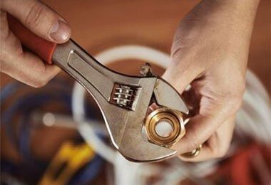Hands Using an Adjustable Wrench to Tighten a Brass Fitting — Weav Plumbed in Emerald, QLD