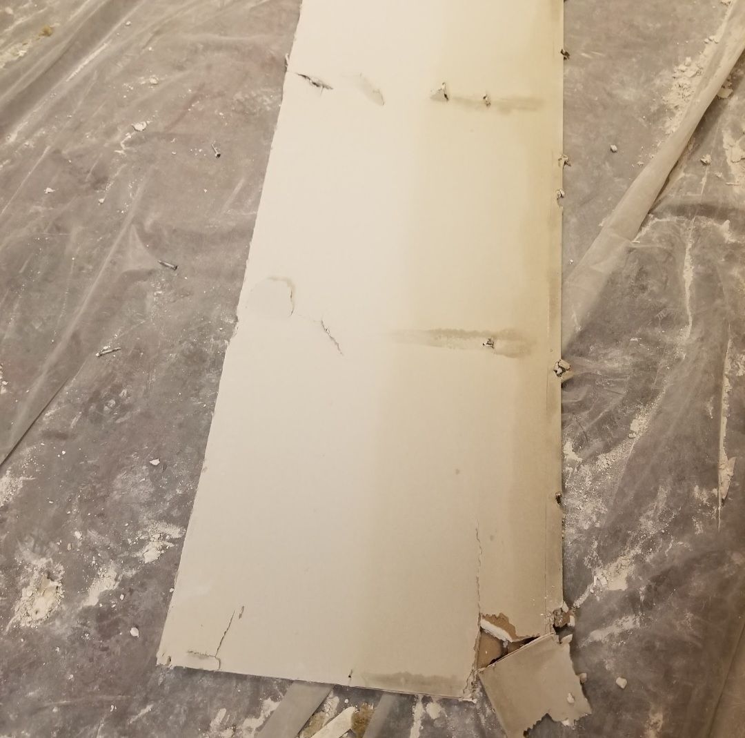 White painted trim with damage on a drop cloth.